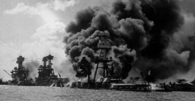 The USS Arizona burning furiously in Pearl Harbour (Pearl Harbor) after the Japanese attack. To the left of her are USS Tennessee and the sunken USS West Virginia. (Photo by Hulton Archive/Getty Images)