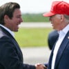 President Donald Trump and Florida Gov. Ron DeSantis shake hands on an airport tarmac.